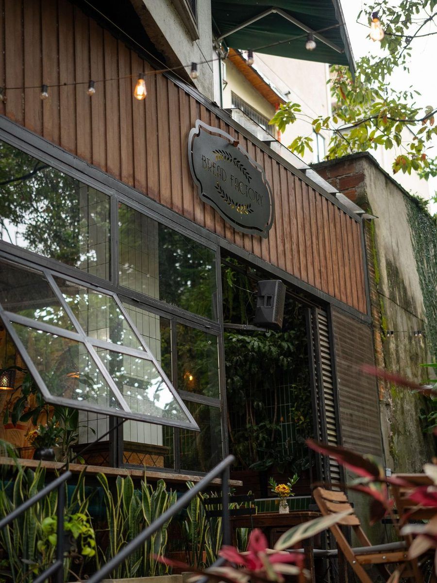 The wooden façade of Bread Factory with its sign, large windows and string lights, seen from the garden